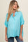 woman wearing a turquoise short sleeve blouse with a button-up front and relaxed fit