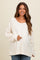 woman wearing a cream long sleeve maternity top with a relaxed fit and textured panel details, holding her baby bump