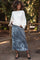 woman wearing a cream oversized sweater and a gray velvet maxi skirt, styled as maternity wear in a natural setting