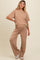 woman wearing a beige maternity lounge set with a short sleeve top and wide leg pants, showing a baby bump