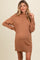 woman wearing a cozy brown maternity sweater dress with a ribbed hem and a relaxed fit, showing her baby bump