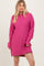 woman wearing a bright pink oversized sweater dress with long sleeves and side slits