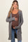 woman wearing a gray long cardigan over a brown ribbed tank top and holding her baby bump