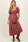 woman wearing a burgundy striped maternity dress with puff sleeves and a smocked bodice, showing her baby bump