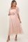 woman wearing a blush pink lace maternity dress with puff sleeves and a square neckline, holding her baby bump
