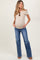 woman wearing a beige v-neck maternity top and light blue flared jeans, showcasing her baby bump