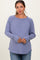 woman wearing a purple long sleeve maternity top with a scoop neckline and curved hem, gently holding her baby bump