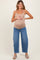 woman wearing a nude maternity tank top and blue wide-leg jeans, holding her baby bump