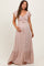 woman wearing a blush pink maternity maxi dress with flutter sleeves and a smocked bodice, holding her baby bump
