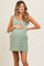 woman wearing a light green maternity tank dress with side stripes and holding her baby bump