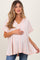woman wearing a light pink striped maternity top and holding her baby bump