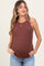 woman wearing a rust ribbed maternity tank top and showcasing her baby bump with hands in pockets