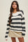 woman wearing a striped black and cream oversized sweater paired with a beige mini skirt