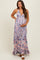 woman wearing a pink and blue floral maternity maxi dress with halter neck and ruffled hem, holding her baby bump