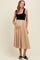 woman wearing a black sleeveless maternity dress with a beige skirt and holding her baby bump