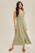 woman wearing a sage green smocked bodice maxi dress with buttons and straps, styled with brown slip-on shoes