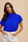 woman wearing a bright blue short sleeve top with a high neckline and white high-waisted pants