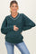 woman wearing a dark green maternity sweatshirt with a v-neck and white detailing, showing her baby bump