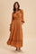 woman wearing a rust-colored long sleeve maxi dress with a tiered skirt and drawstring waist