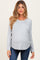 woman wearing a gray long sleeve maternity top with a visible baby bump and blue jeans