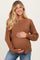 woman wearing a rust ribbed maternity sweater and holding her baby bump