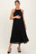 woman wearing a black pleated maternity dress and holding her baby bump