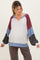 woman wearing a multi-colored striped maternity top with a v-neck and loose sleeves, showing her baby bump