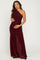 woman wearing a burgundy one-shoulder maternity dress with ruching, holding her baby bump