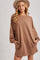 woman wearing a brown oversized sweatshirt dress with long sleeves and pockets, styled with a tan hat