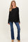 woman wearing a black maternity top with long sleeves and a relaxed fit, paired with blue flared maternity jeans and smiling