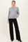 woman wearing a gray maternity sweater and black wide-leg pants, showcasing her baby bump