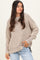 woman wearing a beige oversized ribbed sweater with dropped shoulders and side slits, styled with light blue jeans