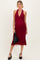 woman wearing a burgundy halter neck maternity dress showcasing her baby bump and holding a black clutch handbag