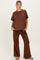 woman wearing a brown maternity loungewear set with a relaxed top and wide-leg pants, hands in pockets