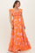 woman wearing an orange floral maternity maxi dress with ruffled sleeves and a tie waist detail, showing her baby bump