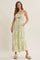 woman wearing a floral maxi dress with a ruched bodice and adjustable straps, standing with hands in pockets