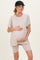 woman wearing a beige maternity top with rolled sleeves and holding her baby bump, paired with matching bike shorts