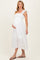 woman wearing a white maternity dress with ruffled straps and eyelet detailing, holding her baby bump