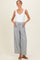 woman wearing a white sleeveless maternity top and striped wide-leg maternity pants with side pockets