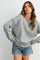 woman wearing a gray striped oversized sweater with a ribbed hem and distressed denim shorts