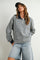 woman wearing a striped gray and navy long sleeve polo shirt with oversized sleeves and denim shorts