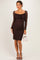 woman wearing a brown lace maternity dress with long sleeves and a fitted silhouette, holding a small white handbag
