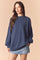 woman wearing a navy blue oversized sweatshirt with balloon sleeves and a relaxed fit paired with a denim mini skirt