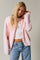 woman wearing a soft pink oversized cardigan with buttons over a white top and high-waisted jeans