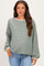 woman wearing a green striped maternity top with long sleeves and a relaxed fit, styled with light blue jeans