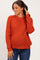 woman wearing an orange knit maternity sweater with long sleeves and a relaxed fit