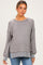 woman wearing a gray striped maternity sweater with long sleeves and side slits, styled with blue jeans