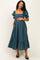 woman wearing a green maternity dress with puff sleeves and a tiered ruffle hem, holding her baby bump