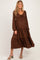 woman wearing a brown maternity dress with a tiered, ankle-length design and a drawstring neckline, showcasing her baby bump