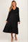woman wearing a black maternity dress with puffed sleeves and a ruffled hem, showcasing her baby bump